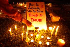 A participant lights a candle next to a sign during a vigil for the Indian rape victim in Singapore