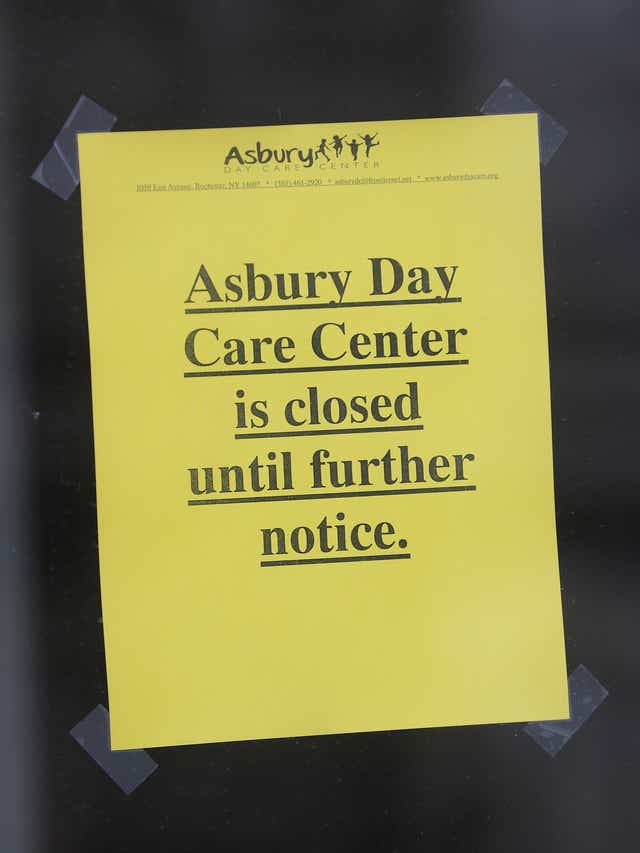 A yellow typed sign posted on a door that reads "Asbury Day care Center is closed until further notice." in bold font