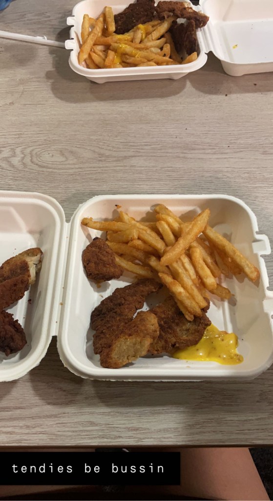 Photograph of the blackened chicken tenders, the photo shows two to-go boxes on a table with fries and burnt chicken tenders