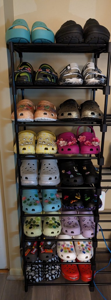 18 pairs of Crocs arranged on a shoe tower, with different colors and accessories for each. Meant to supplement the reading.