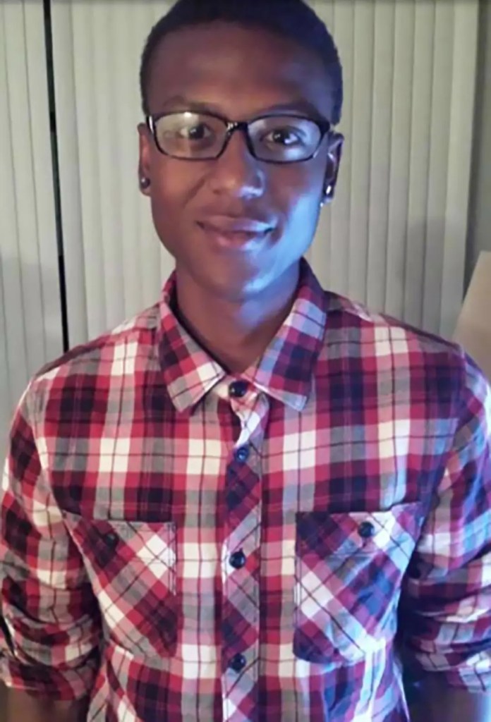 Family photo of Elijah McClain wearing red plad shirt and black glasses.