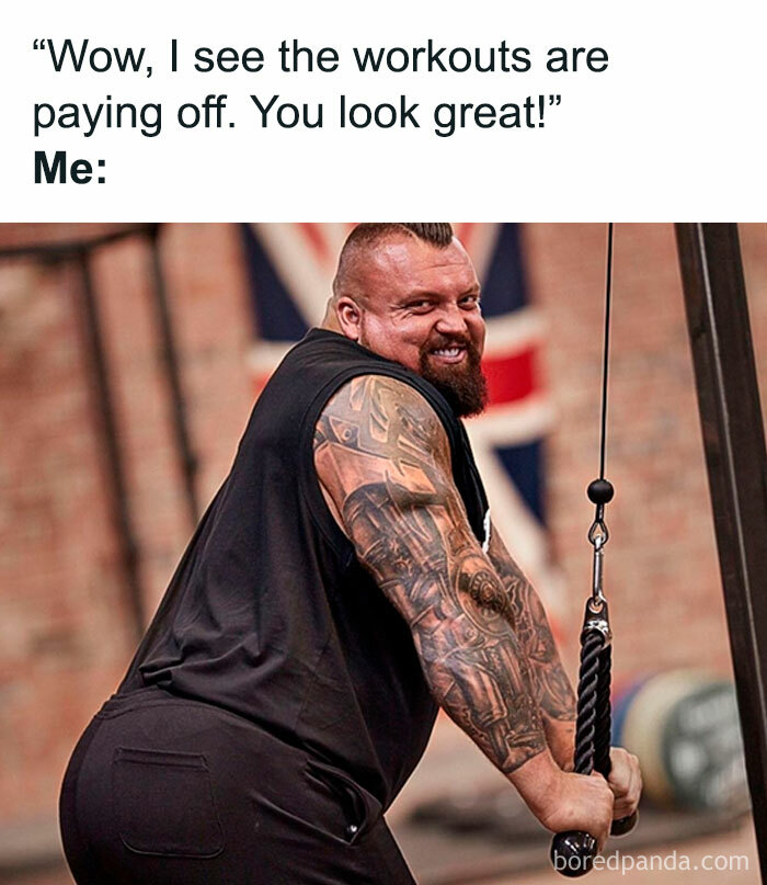 strong body builder man with that tattoos and a terrible mohawk hair cut in a sassy pose smiling is the cable machine doing lateral pull downs and the meme says wow I see the workouts are paying off you look great
